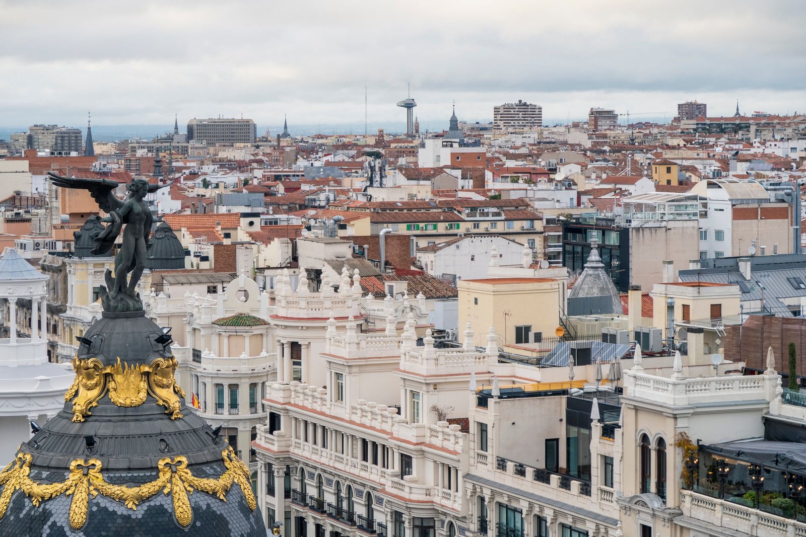 A captivating view of Madrid's iconic Metropolis Building amidst historic rooftops.