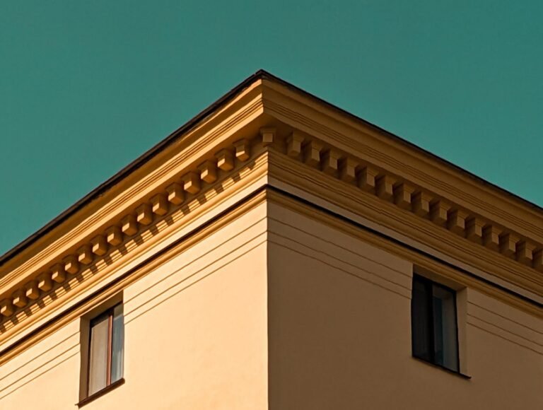 A yellow building with decorative edges photographed against a vibrant teal sky.