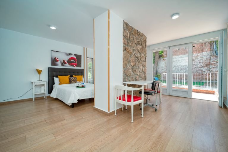 Stylish minimalist bedroom with stone partition and natural light, featuring wooden floors and modern decor.
