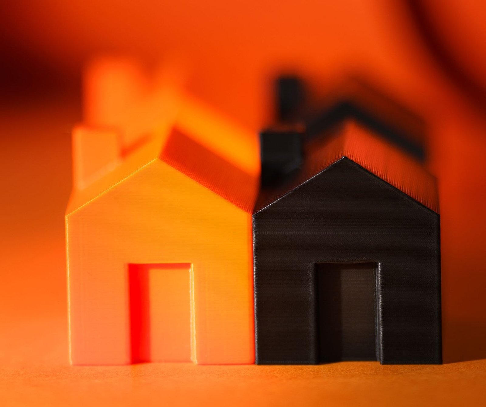 Vibrant and contrasting orange and black miniature house models symbolizing real estate concepts.